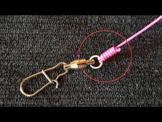 a pair of scissors is hooked up to a pink cord on a black surface with red thread