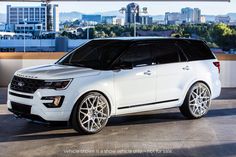 a white suv parked in front of a city skyline