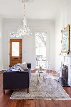 a living room filled with furniture and a chandelier hanging from the ceiling over a fire place