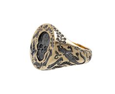 This edgy, hand engraved Castro Smith signet ring has a bold vibe and eye-catching design. The 9K yellow gold band has been carved with bones, skeletons, frogs and leaves. The round ring face has a detailed surface with leaves, spiders, bones and one large skull at its center. Each engraved part has been plated in black rhodium. A tiny engraved flower sits on the inside of the band for a secret for only the wearer. ring face : 3/4" x 5/8"9K yellow gold and black rhodium plated band width : 5mmsize available : 10please contact us for sizing options Castro Smith, Daniela Villegas, Digby And Iona, Rebecca Overmann, Engraved Flower, Zoe Chicco, Cathy Waterman, Single Stone, Round Rings