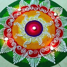 a colorful rangdi with candles in the center on a green and white circle rug