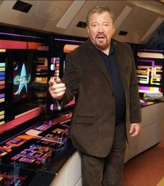 a man standing in front of a bunch of pinball machines holding a remote control