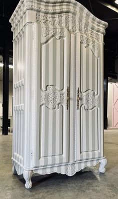 an ornately decorated armoire sits in the middle of a room with black and white striped walls