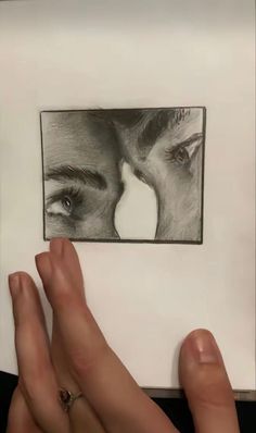 two hands are touching each other in front of a drawing of a man and woman's face