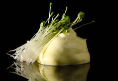 a piece of artichoke sitting on top of a black table next to water