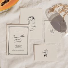 the wedding stationery is laid out on top of the table with fruit and paper