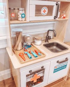 a wooden play kitchen with sink, stove and cabinets