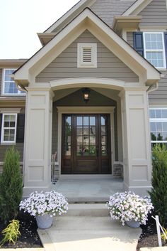 the front entrance to a house with two large planters