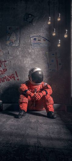 an astronaut sitting on the ground in front of a wall with graffiti and light bulbs