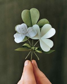 a person is holding some paper flowers in their hand and they are tied together with twine