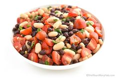 a white bowl filled with beans and tomatoes