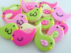 decorated cookies with pink, green and yellow icing on white surface next to each other