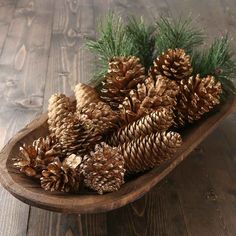 some pine cones are in a wooden bowl