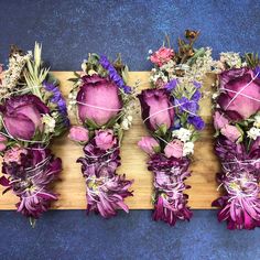 purple flowers are arranged on a wooden board