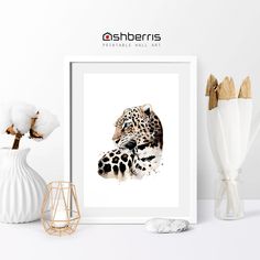 a white vase with cotton flowers and a framed print of a leopard's head