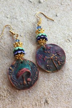 the earrings have been made from an ancient coin and are adorned with gold - plated beads