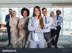 group of business people standing together in an office building with their arms crossed and smiling at the camera