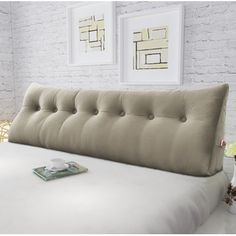 a bed with a pillow on top of it next to two pictures and a lamp