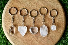 five key chains with different shapes and sizes of rocks on them, sitting on some grass