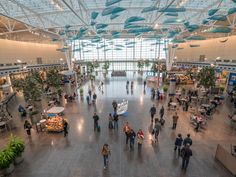 people are walking through an airport terminal with lots of plants on the walls and ceiling