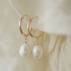 Designer: OFINA An everyday classic. Polished pearl mini hoops to give you a classic modern look. Available in 2 sizes. Small Size: 15mm Hoop w/ 7-8mm Freshwater Pearl Large Size: 18mm Hoop w/ 10mm Freshwater Pearl Material & Care 14k Gold Filled Stone: Freshwater Pearl Hypoallergenic Can be worn in water For more info: Jewelry Care How to Wear Lovely alone or stack the two sizes together. Can also be paired with your favorite huggies and studs! Luxury Small Hoop Pearl Drop Earrings, Luxury Everyday Pearl Hoop Earrings, Cheap Hoop Earrings With Pearl Charm, Classic Pearl Huggie Jewelry, Everyday Pearl Earrings With Pearl Charm, Classic Small Hoop Pearl Jewelry, Everyday Pearl Charm Earrings, Classic White Huggie Earrings For Everyday, Classic Pearl White Hoop Earrings