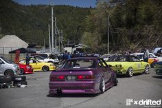 several cars parked in a parking lot with people standing around them and looking at them