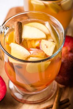 two mugs filled with apple cider and cinnamon sticks on a wooden cutting board