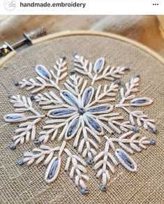 an embroidered snowflake is shown on a piece of burlied fabric, with the words handmade embroidery