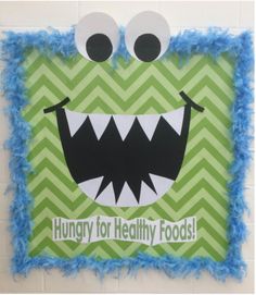 a green and blue wall hanging with a monster face on it's side that says hungry for healthy foods