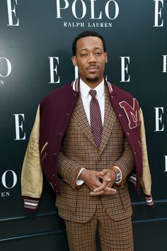 a man wearing a suit and tie standing in front of a polo event sign with his arms crossed