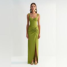 a woman in a long green dress with a slit down the side and her hand on her hip