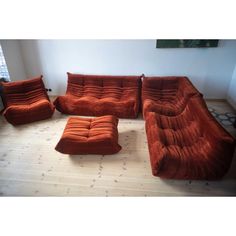 an orange couch and ottoman sitting on top of a hard wood floor