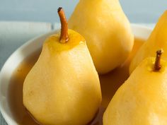 three yellow pears sitting in a white bowl