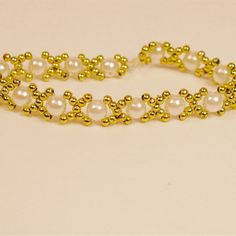 a gold and white beaded bracelet with pearls