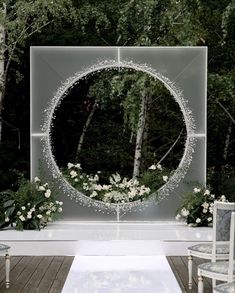 an outdoor ceremony setup with white flowers and greenery in front of a circular mirror