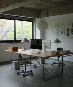 a desk with a computer on it in front of a window