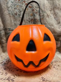 an orange plastic pumpkin shaped like a jack - o'- lantern