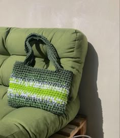 a crocheted bag sitting on top of a green chair next to a wall