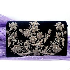 "Shop sustainably and own a handbag that you will cherish forever. Stunning navy velvet zardozi evening clutch bag embroidered with antique silver flowers and inlaid with genuine gemstones, to create an opulent and dazzling 3D effect. Expertly hand embroidered in intricate detail by master zardozi artisans with over 25 years experience. Zardozi means \"gold thread\" or \"writing with gold\". It is an elaborate and intricate art of 3D embroidery using metallic threads and semi precious stones to Elegant Velvet Evening Bag For Wedding, Velvet Rectangular Evening Bag For Wedding, Traditional Handmade Silver Evening Bag, Elegant Velvet Evening Bag Gift, Elegant Velvet Evening Bag As Gift, Elegant Velvet Evening Bag For Gift, Velvet Clutch For Wedding, Hand Embellished Silver Bag For Formal Occasions, Embroidered Velvet Evening Bag