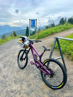 a purple bike parked on the side of a dirt road