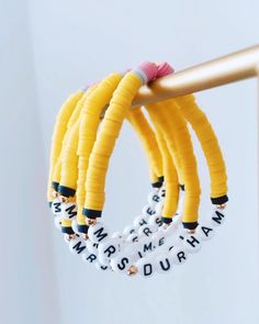 three bracelets are hanging from a metal pole with letters on them and beads around the ends