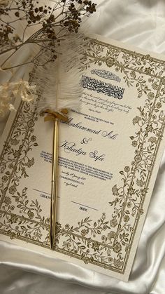 a wedding card with a feather on it and some flowers in the corner next to it