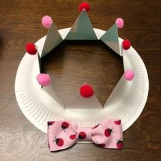 a paper plate with a pink bow tie on it and a crown made out of paper plates