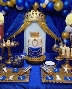 a blue and gold themed birthday party with cake, candles, plates and balloons on the table