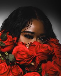 a woman with long black hair holding red roses