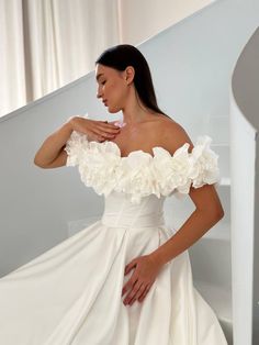 a woman in a white wedding dress standing next to a stair case with her hands on her hips