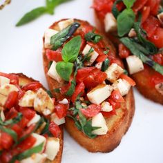 three pieces of bread topped with tomatoes and basil