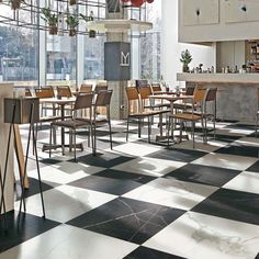 a restaurant with black and white checkered flooring, bar stools and tables