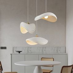 three lights hanging from the ceiling above a table with four chairs and a round dining room table