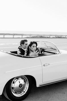 a man and woman are sitting in a convertible car